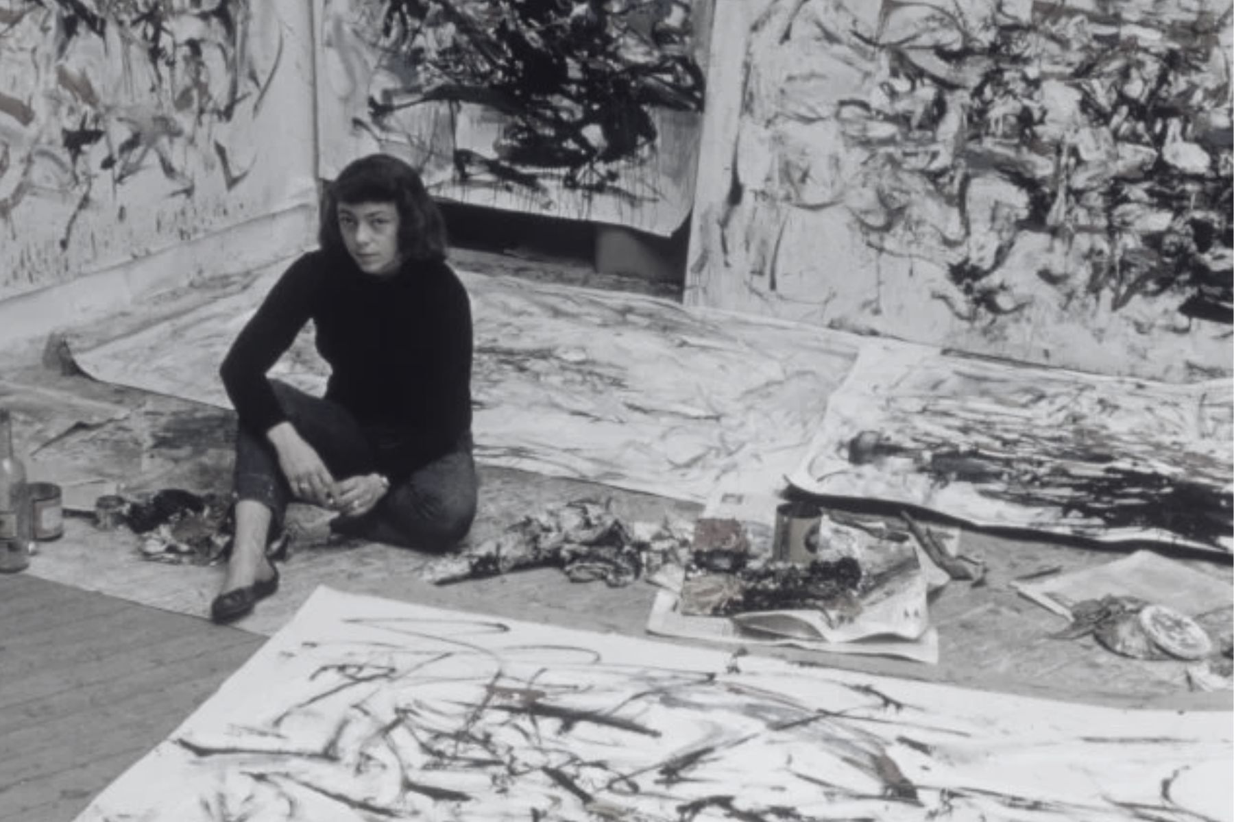 Joan Mitchell seated on the floor in her Paris studio surrounded by large abstract canvases