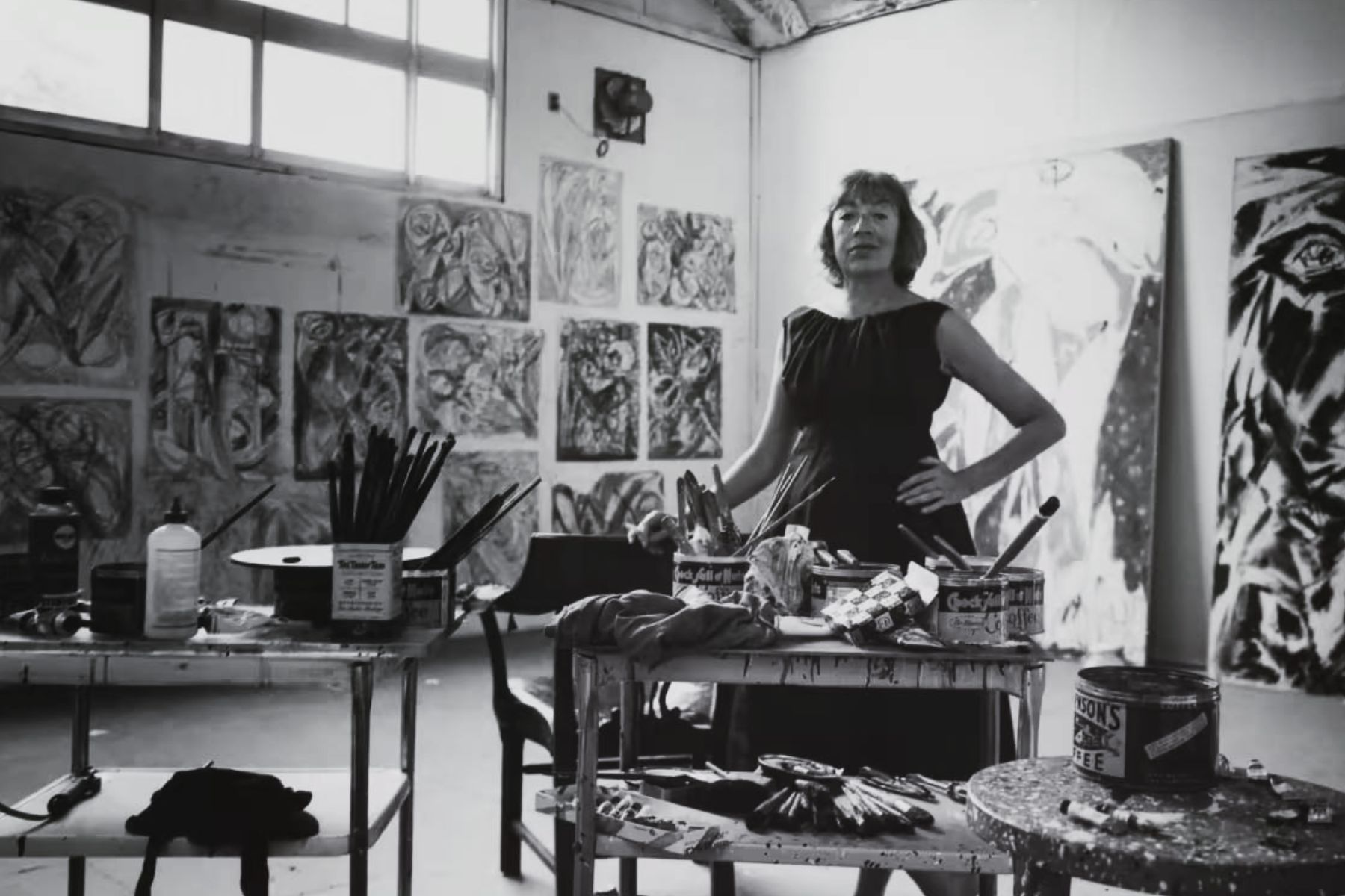 Lee Krasner standing in her East Hampton studio surrounded by paintings and tools