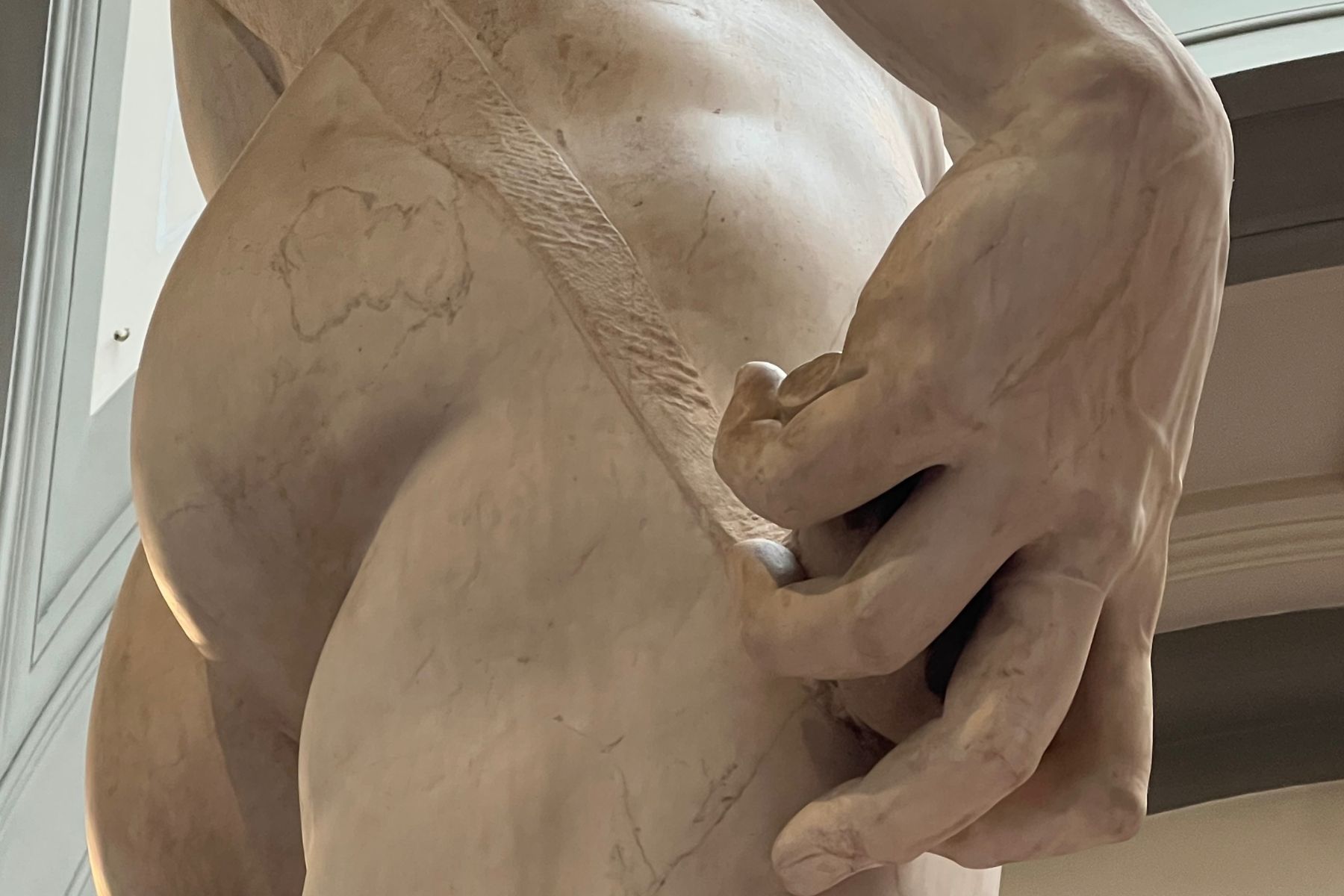 Close-up detail of David’s hand grasping a slingshot