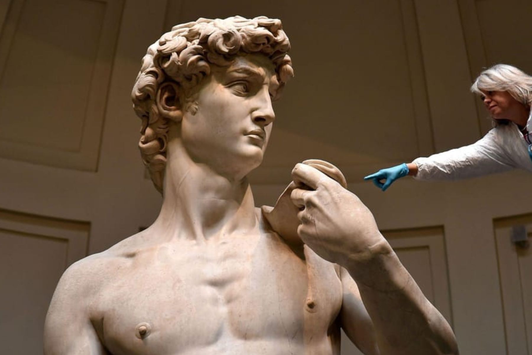 Michelangelo’s David sculpture with a conservator examining the marble surface
