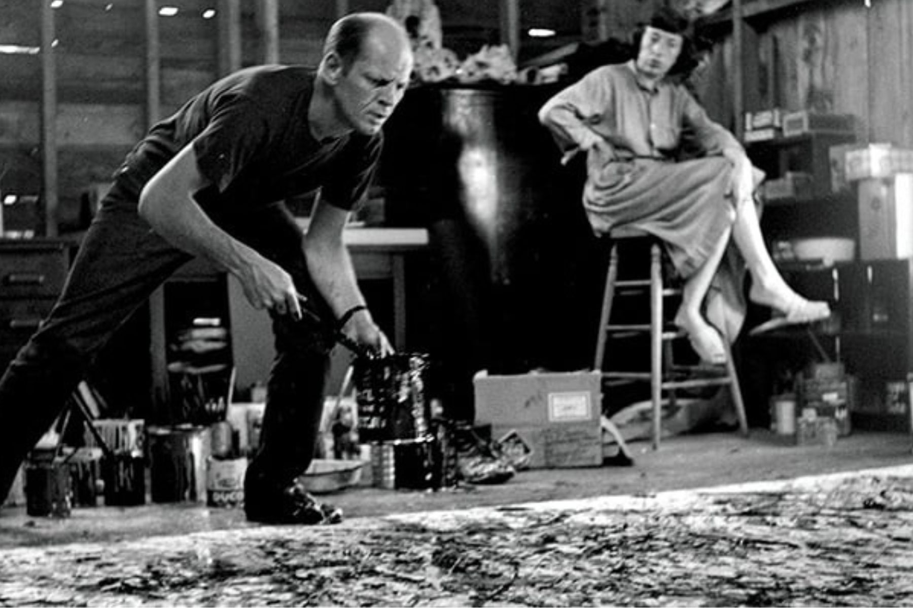 pollock-krasner-studio-hans-namuth-1950-the-lawless-muse Jackson Pollock painting in his studio using his signature drip technique while Lee Krasner watches nearby seated in chair